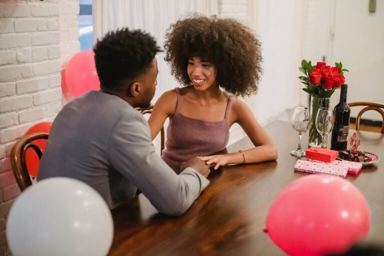 Couple celebrating an anniversary at a restaurant table with roses and a gift